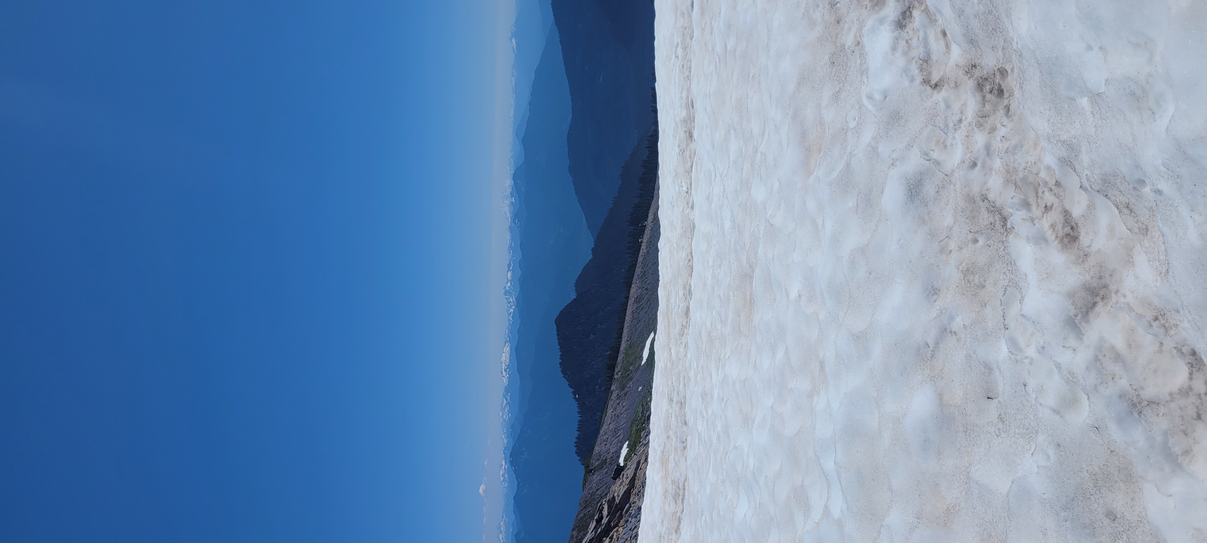 Looking down the glacier from high on Baker — snow field, exposed rock, blue sky