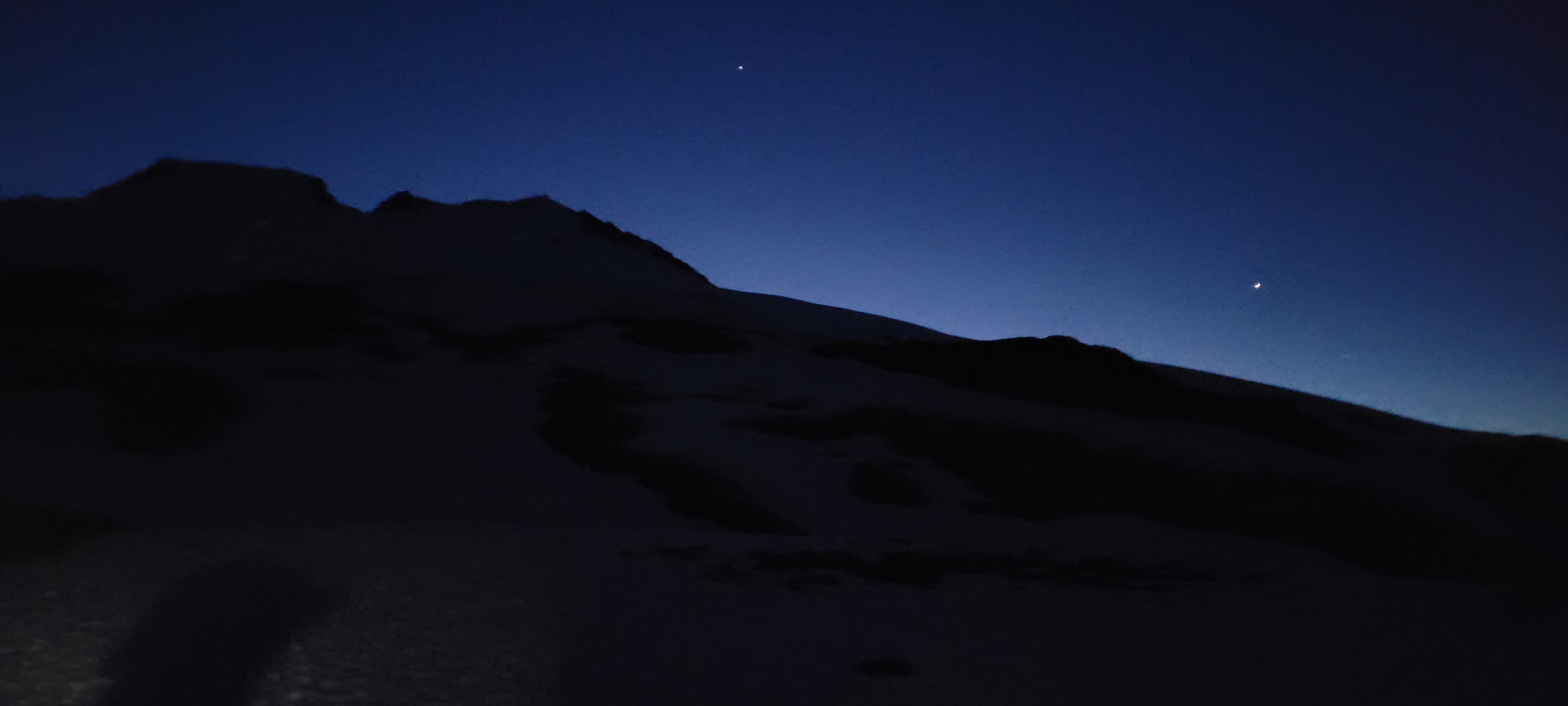 Mt. Baker silhouette against a deep blue pre-dawn sky, two stars visible