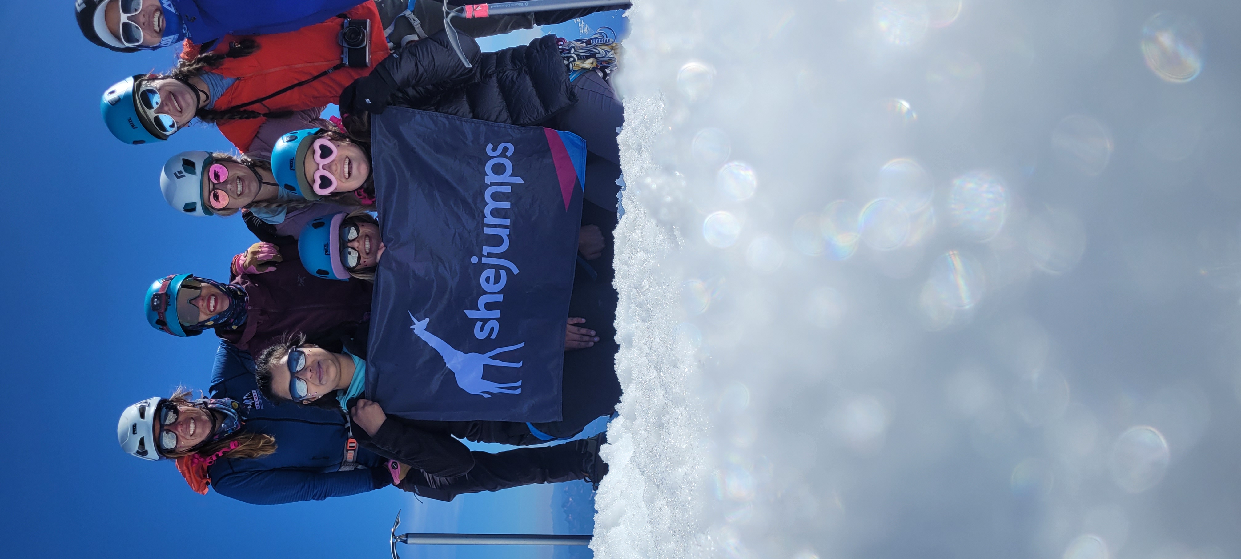 Nine women on the summit holding a SheJumps flag