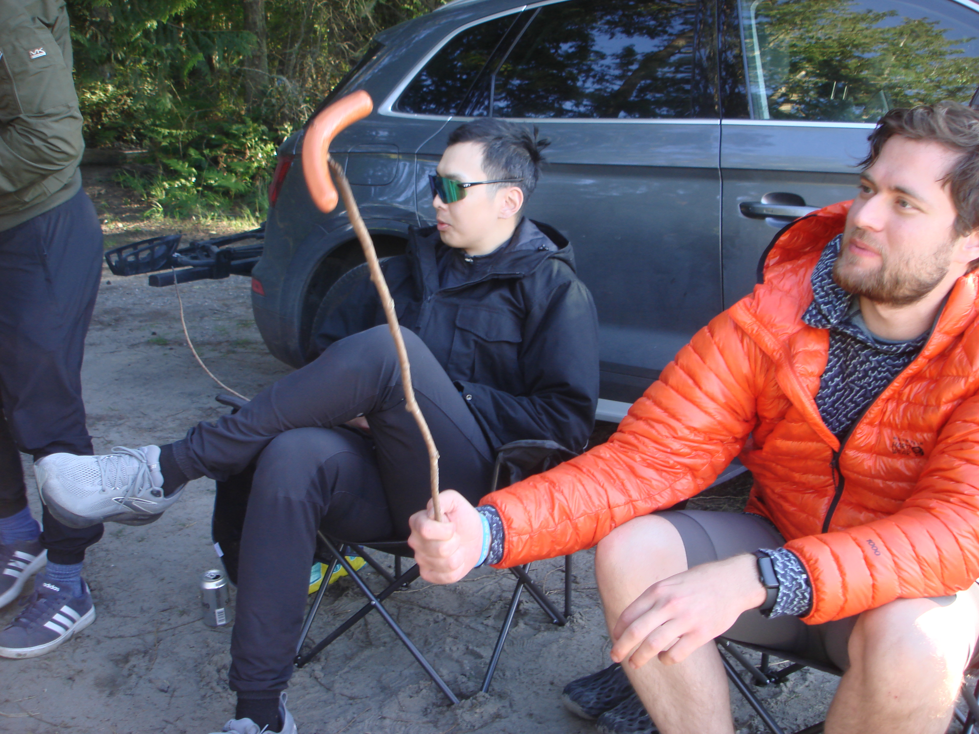 Two people at the campfire, roasting a hot dog on a stick