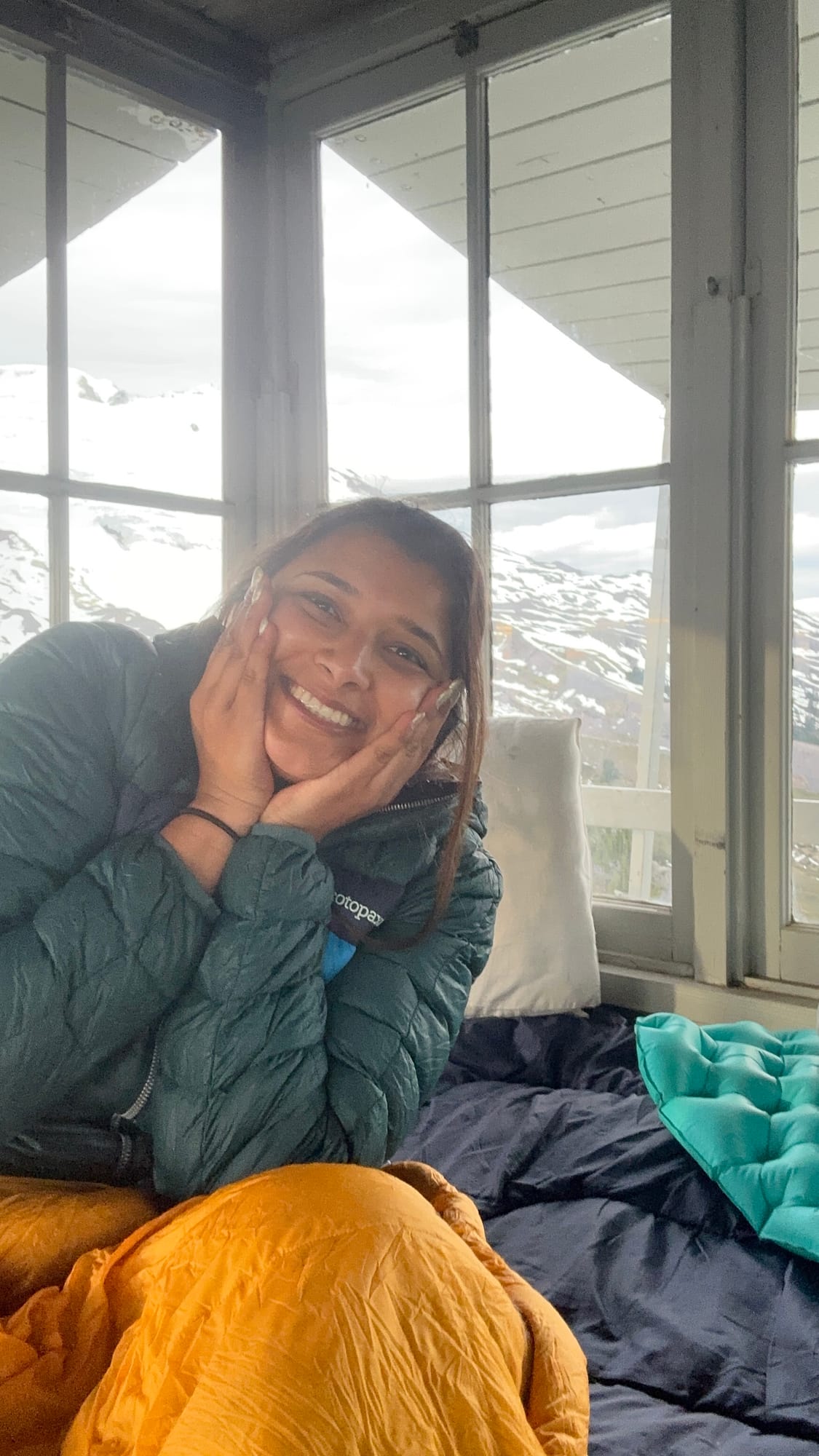 Morning in the lookout — smiling in a sleeping bag with Baker through the window