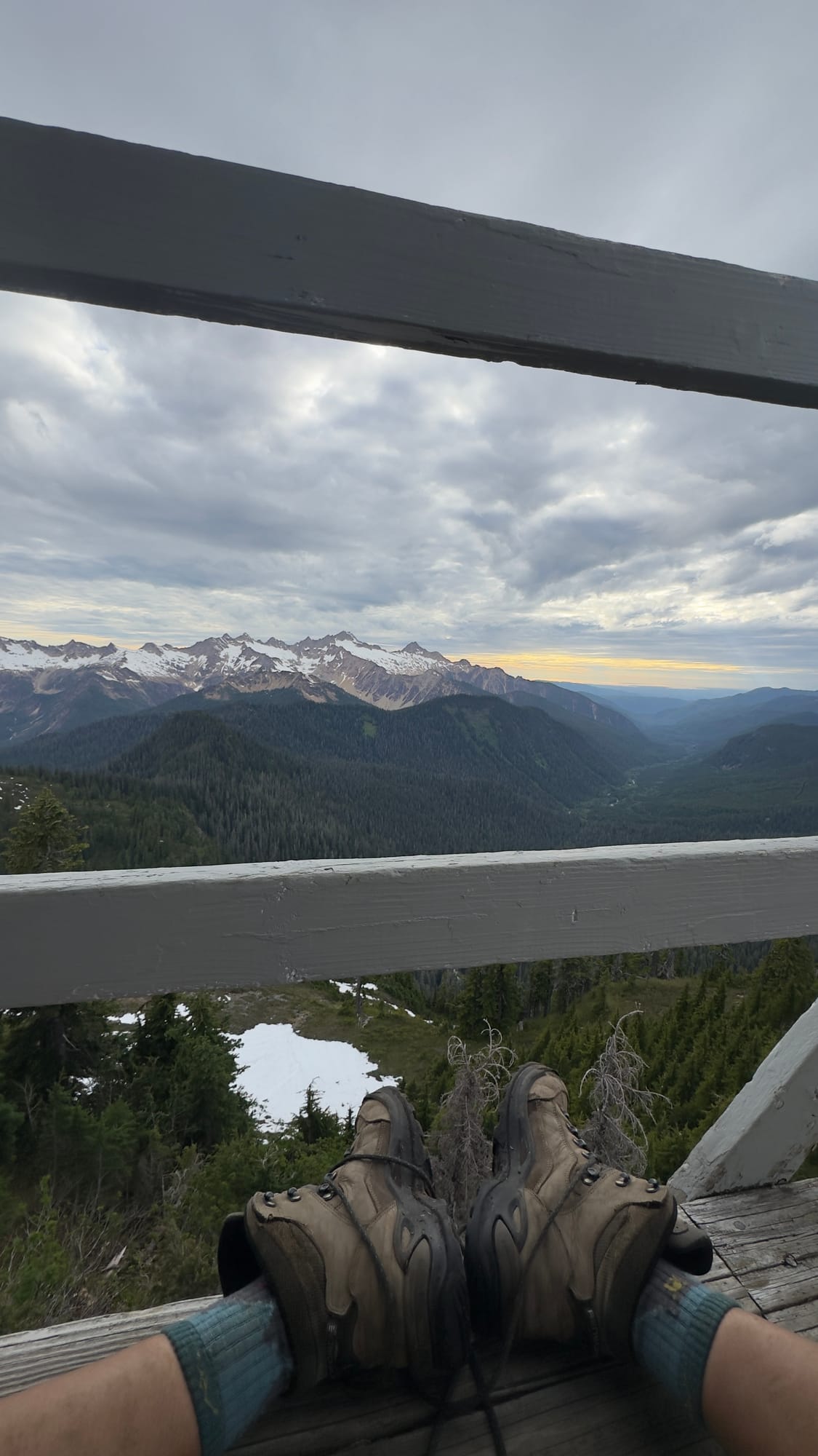 Feet in boots on the lookout porch railing overlooking the Cascades
