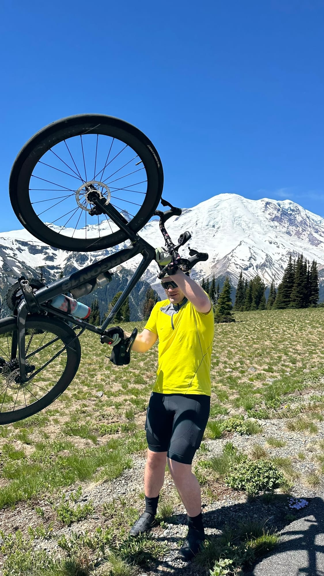 Friend lifting bike overhead with Rainier right there behind
