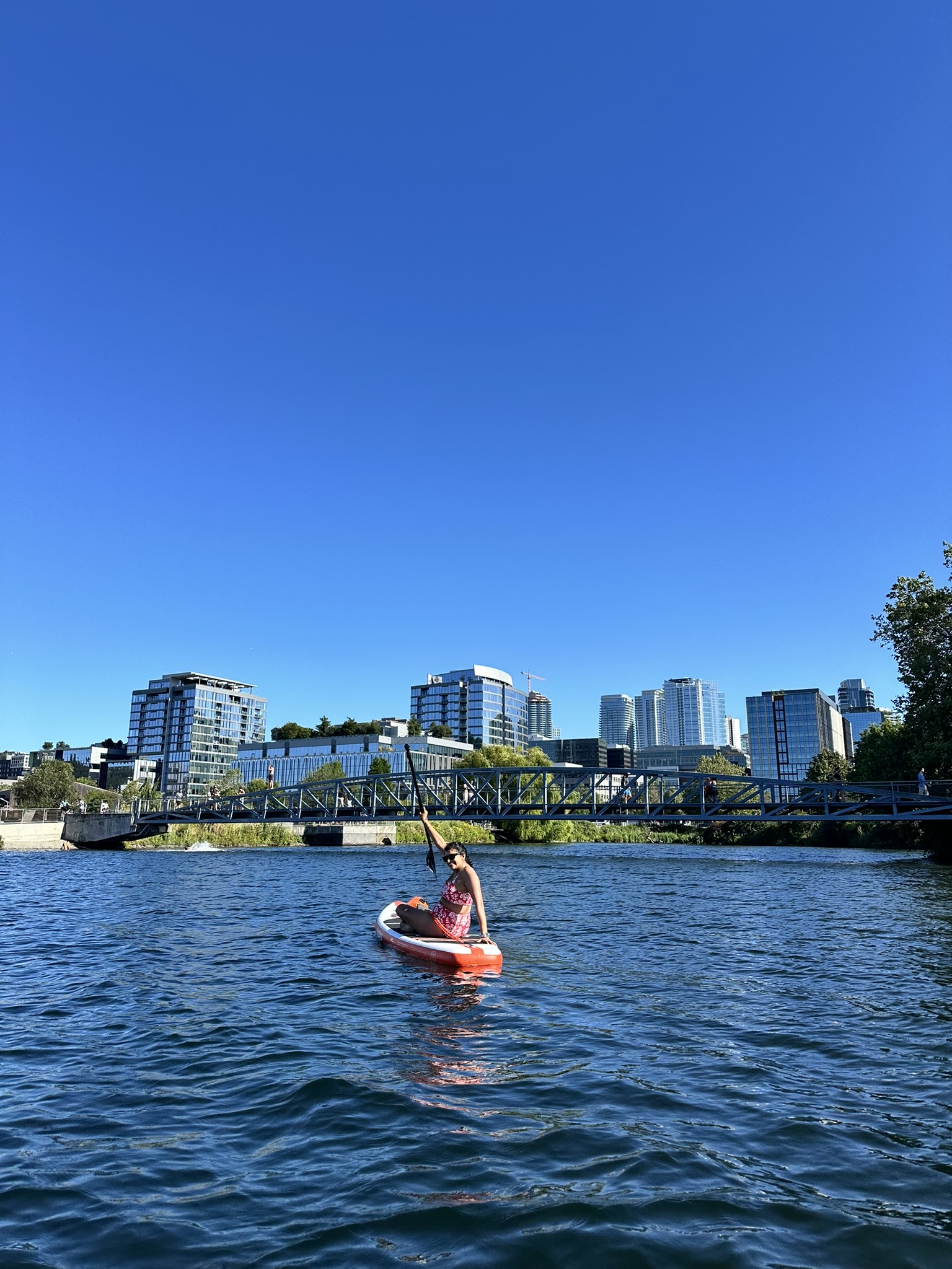Saachi on a paddleboard on Lake Union, Seattle skyline and Eastlake bridge behind