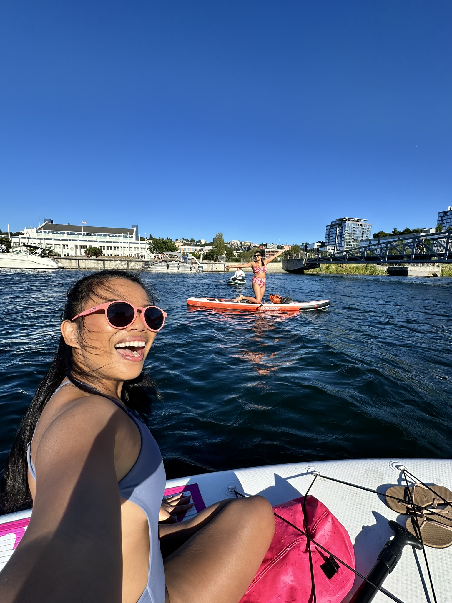 Saachi and a friend on paddleboards on Lake Union, South Lake Union buildings behind