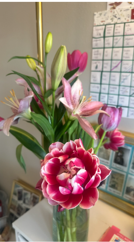 A bouquet of pink tulips and lilies in a glass vase on my desk